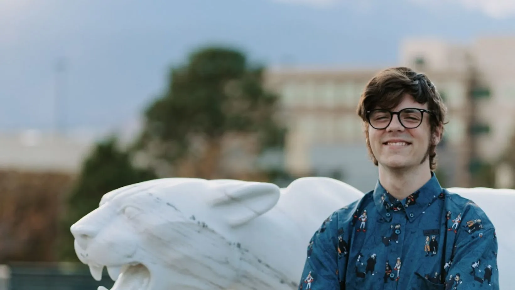 photo of Aidan Clark next to the mountain lion statue on uccs campus